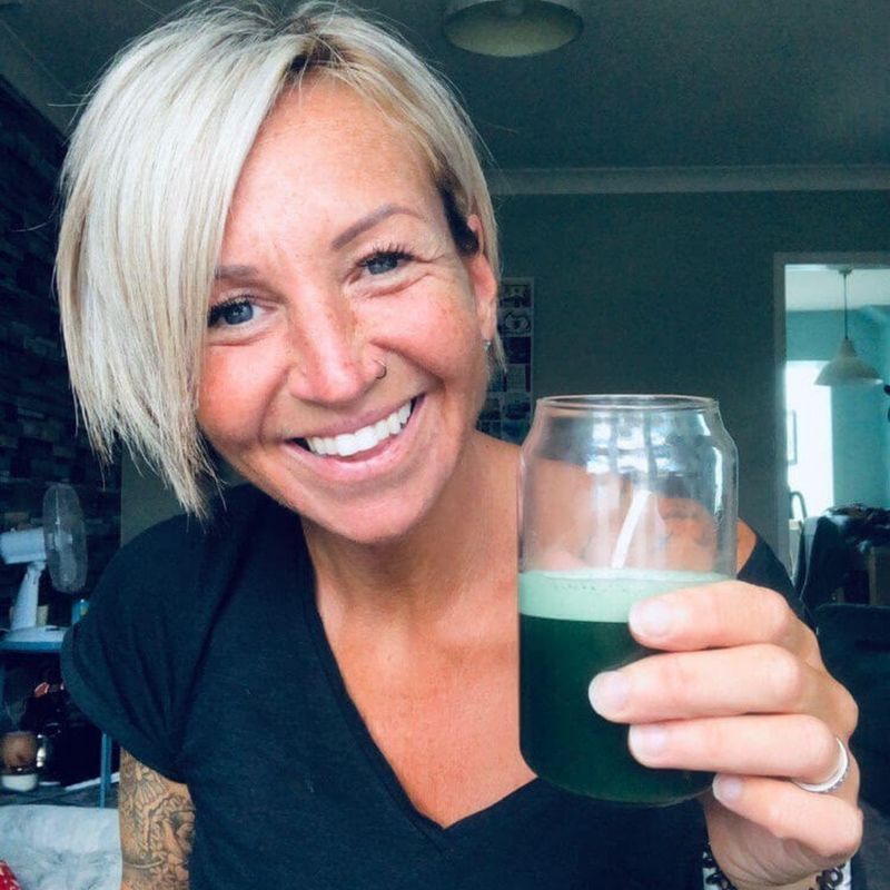 Hence Greens customer holding a glass of mixed greens powder — daily serving ready to drink
